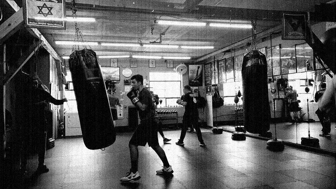 Member hitting the heavy bag while a coach watches